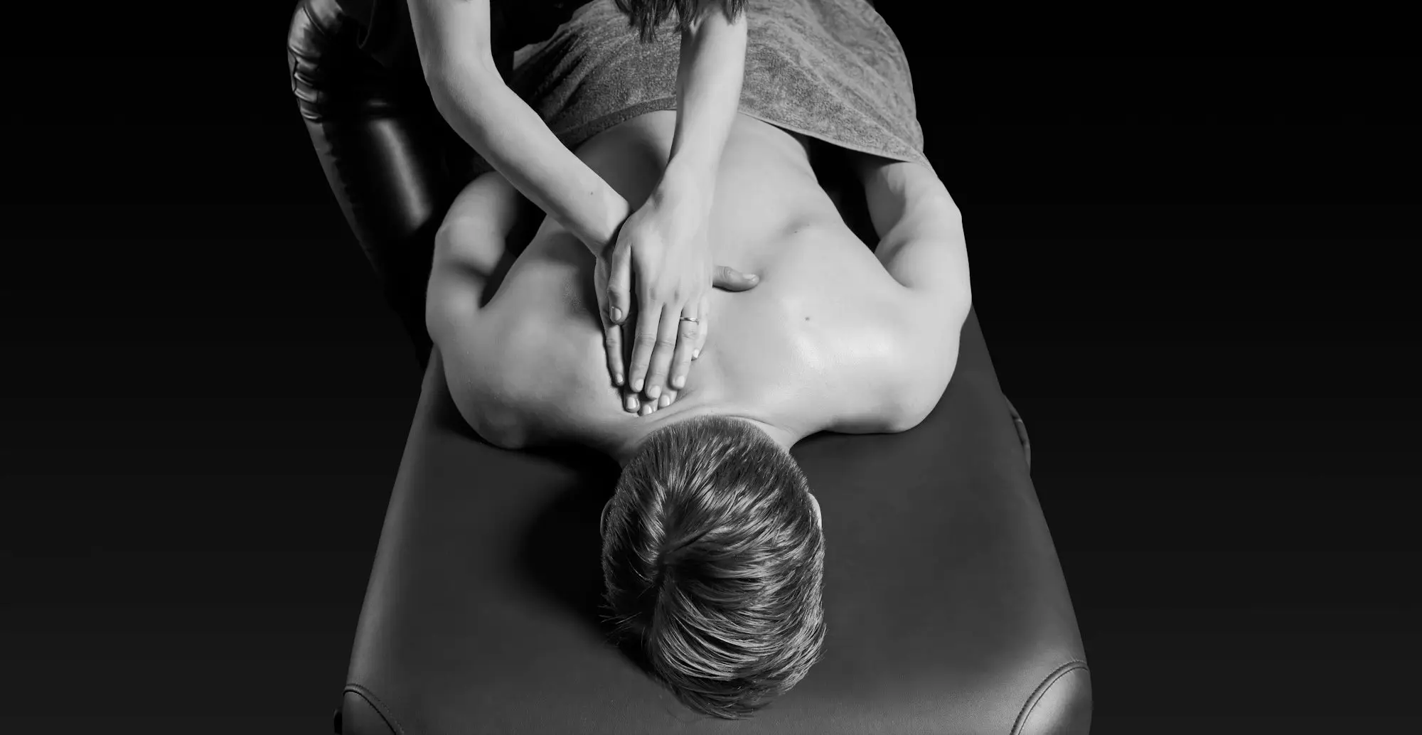 Hands working down a back on a massage table, seen from above.